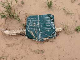 A quite weathered roadsign lying in the desert sand